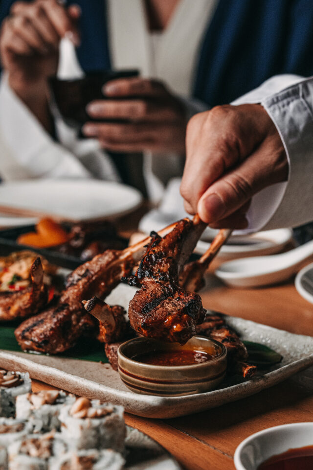 A person is dipping roasted meat in sauce for RAMADAN Iftar from dining table